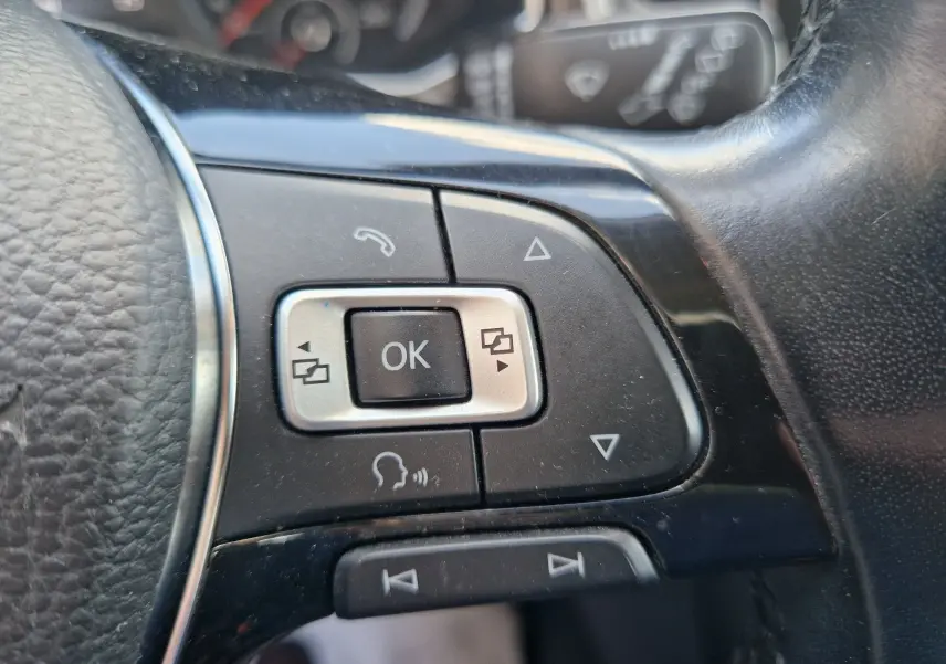 Gros plan sur les commandes multifonctions à droite du volant cuir noir du Volkswagen T-Roc Lounge chêne noir.