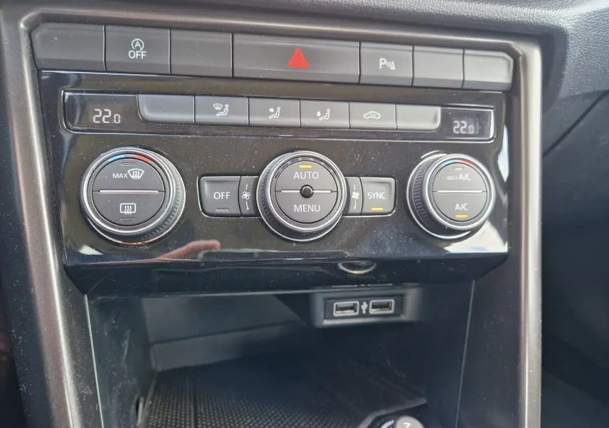 Vue rapprochée de la console centrale du Volkswagen T-Roc chêne noir, montrant les commandes de climatisation automatique et deux ports USB.