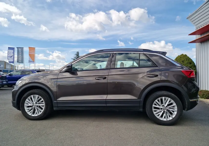 Vue de profil côté gauche d'un Volkswagen T-Roc chêne noir avec jantes alliage et toit noir, stationné en extérieur.