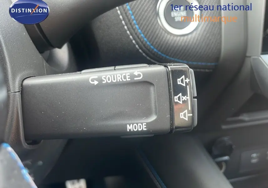 Gros plan sur la commande multimédia au volant d'un Renault Captur gris Cassiopée avec surpiqûres bleues.