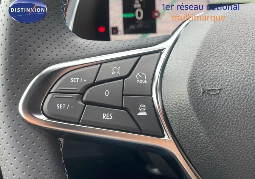 Gros plan sur les commandes au volant du Renault Captur E-Tech hybride 2025, avec cuir perforé gris et boutons fonctionnels.