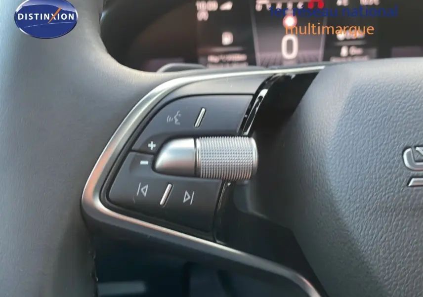 Gros plan sur les commandes multifonctions au volant d'un Skoda Kamiq gris argent, avec tableau de bord numérique en arrière-plan.