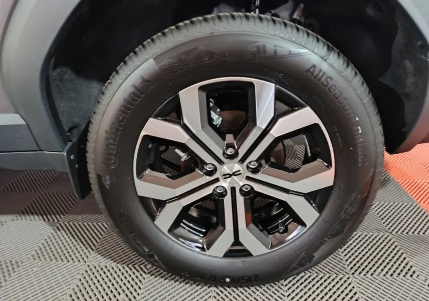 Gros plan sur la roue avant droite du Dacia Bigster gris foncé, mettant en valeur la jante noire et argentée au design moderne.
