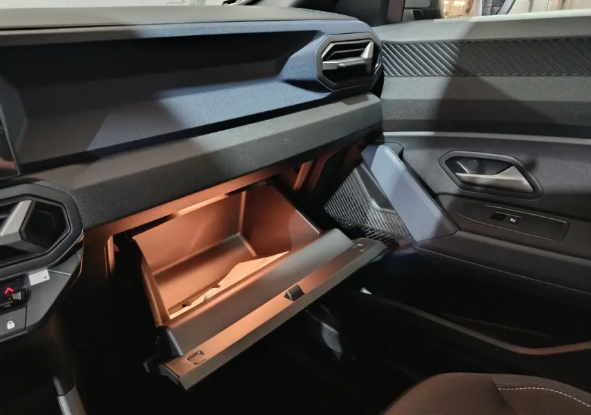 Vue intérieure côté passager du tableau de bord gris foncé du Dacia Bigster 2025 avec boîte à gants ouverte.