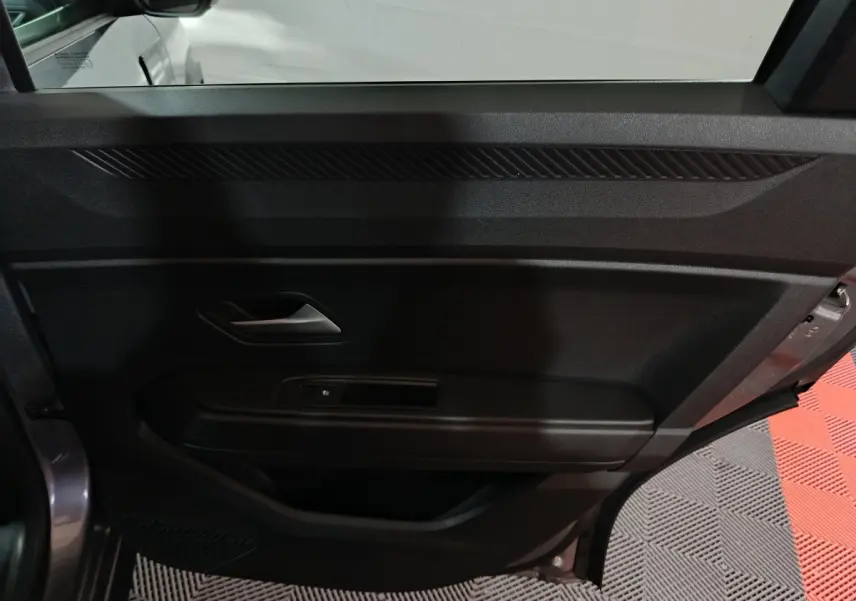 Vue intérieure du panneau de porte côté gauche gris foncé du Dacia Bigster 2025 avec poignée et commande de vitre électrique.