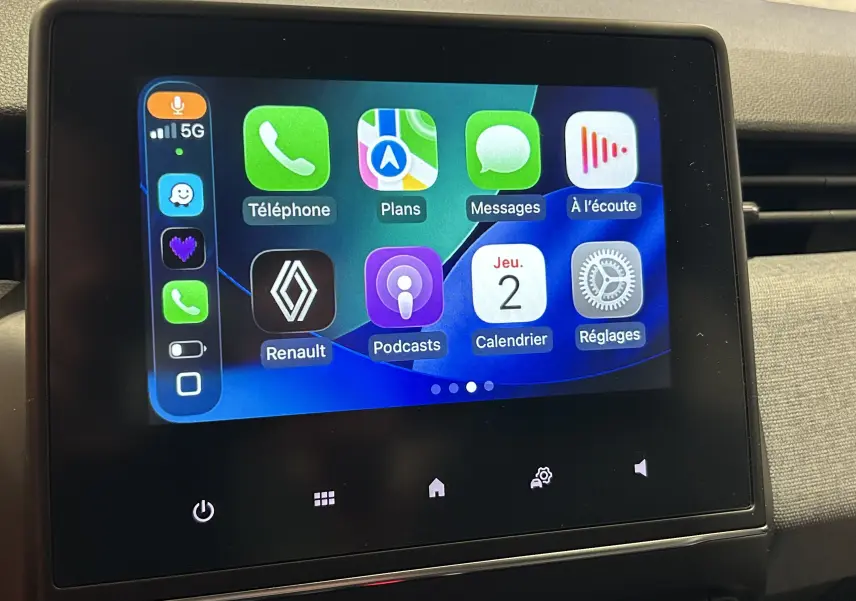 Écran tactile central affichant l'interface Apple CarPlay dans une Renault Clio V blanche, vue intérieure frontale.
