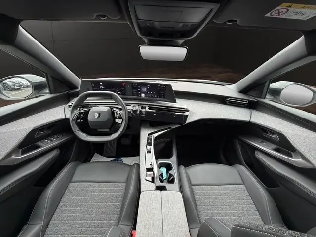 Vue intérieure avant du Peugeot 5008 blanc 2025, tableau de bord numérique et volant compact multifonctions en cuir.