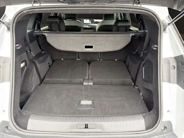 Coffre ouvert du Peugeot 5008 blanc, vue arrière montrant les sièges rabattus et la tablette cache-bagages.