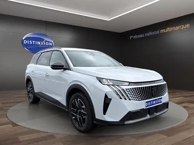 Peugeot 5008 blanc en 3/4 avant droit, avec calandre distinctive et jantes noires brillantes.