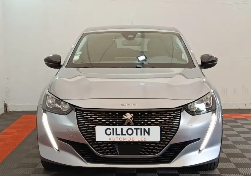 Vue frontale d'une Peugeot 208 Electrique Roadtrip gris clair avec feux LED et calandre noire distinctive.