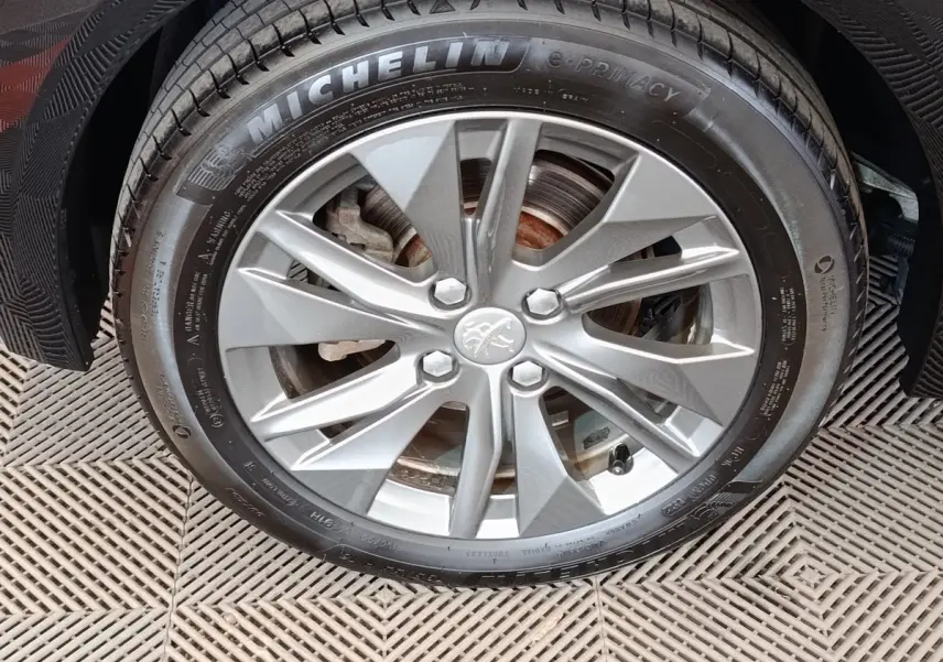 Gros plan sur la roue avant droite de la Peugeot 208 Electrique Roadtrip gris clair avec jante alliage et pneu Michelin.