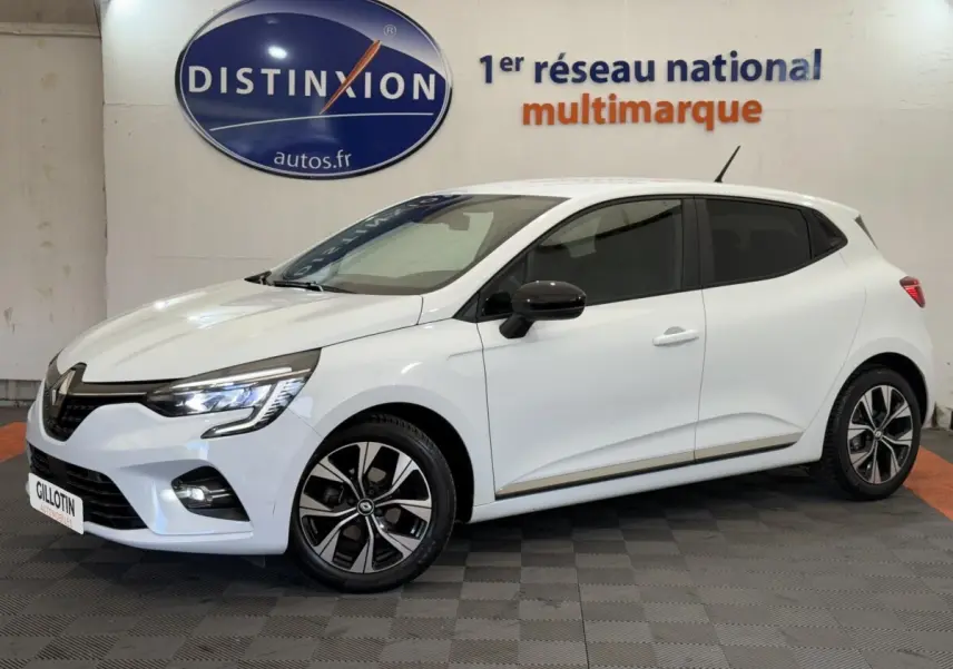 Renault Clio Evolution TCe 100 GPL blanche vue de profil droit en intérieur, avec jantes alliage et rétroviseurs noirs.