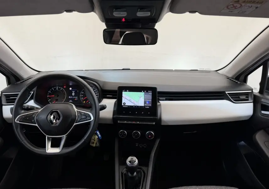 Vue intérieure frontale du tableau de bord de la Renault Clio blanche 2023 avec écran tactile central et volant cuir multifonctions.