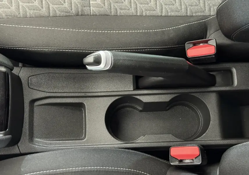 Vue rapprochée de la console centrale noire avec frein à main et porte-gobelets de la Renault Clio blanche Evolution TCe 100 GPL 2023.