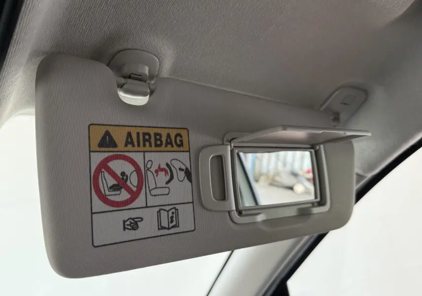 Détail du pare-soleil côté conducteur avec miroir ouvert et avertissement airbag dans une Renault Clio blanche.