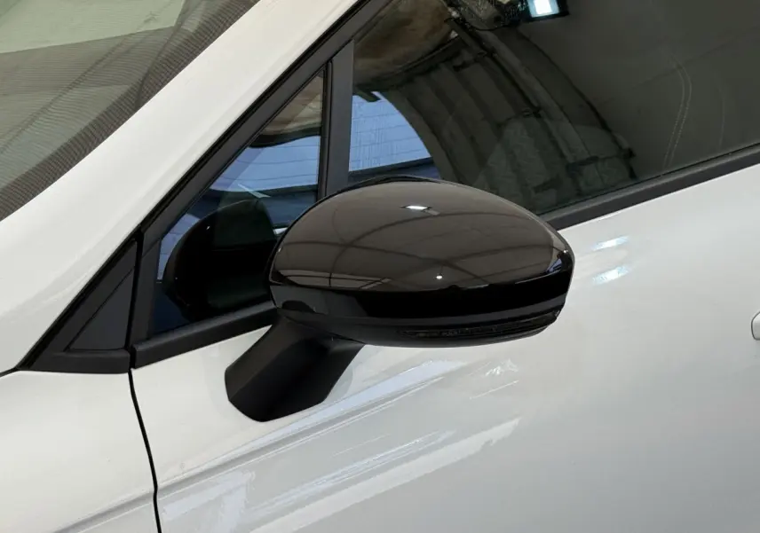 Gros plan sur le rétroviseur noir brillant côté conducteur d’une Renault Clio blanche Evolution TCe 100 GPL 2023.