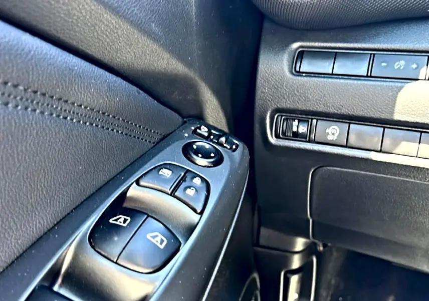 Gros plan sur les commandes de vitres électriques et rétroviseurs côté conducteur du Nissan Juke gris 2025.