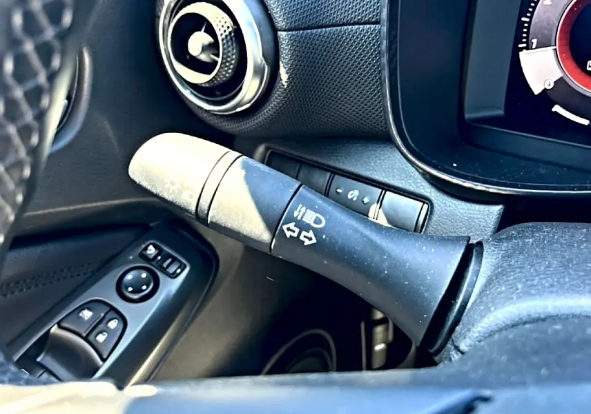 Détail intérieur du levier de clignotant côté gauche du tableau de bord noir du Nissan Juke gris 2025.