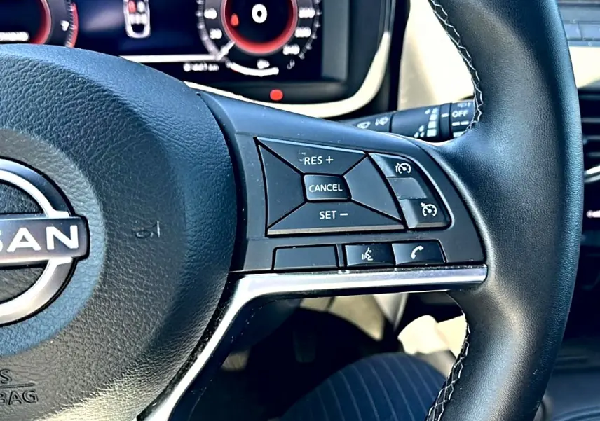 Gros plan sur le volant cuir noir du Nissan Juke 2025, avec commandes multifonctions visibles côté droit.