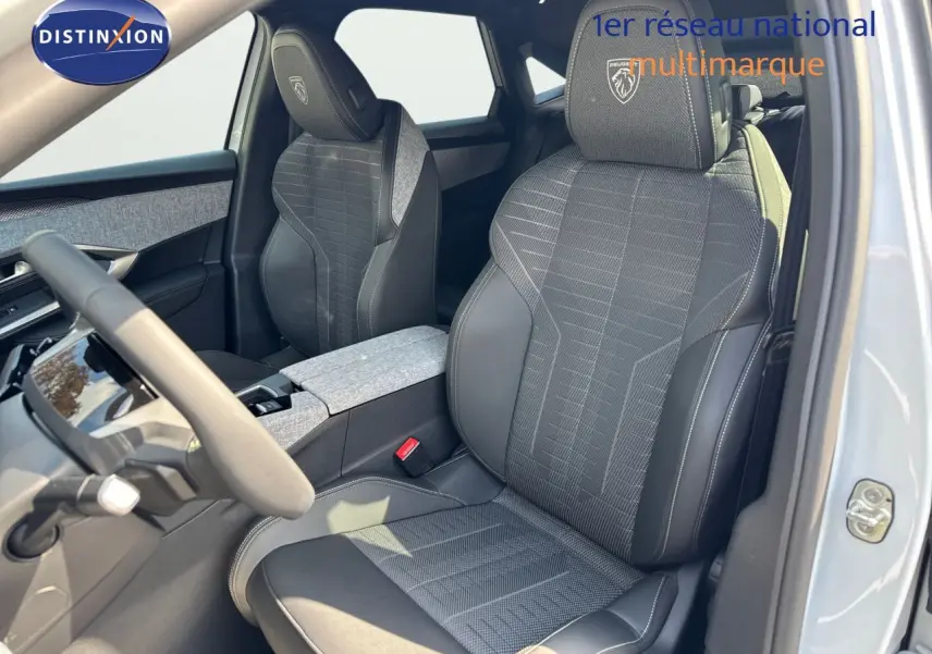 Vue intérieure côté conducteur du Peugeot 3008 blanc Okenite 2025, sièges en tissu et cuir noir avec logo GT brodé.