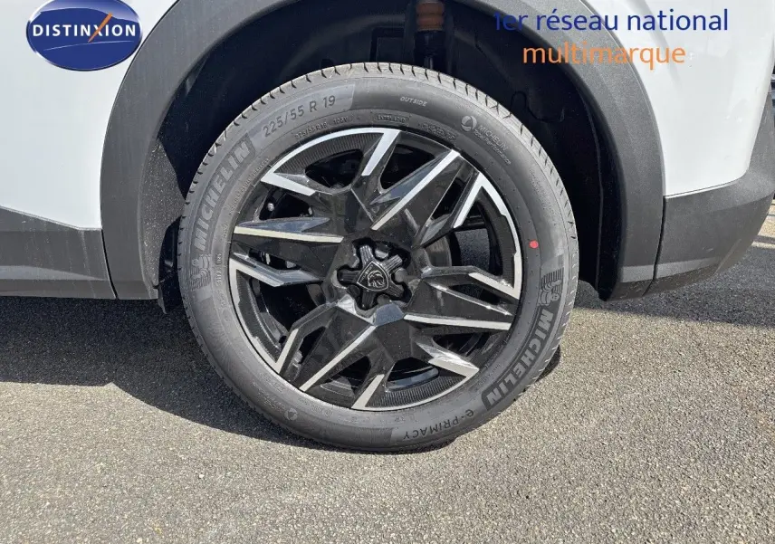 Gros plan sur la roue avant droite du Peugeot 3008 blanc Okenite avec jante noire et argentée design moderne.