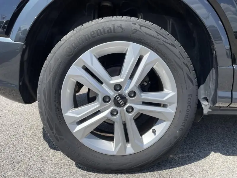 Gros plan sur la roue avant gauche d'un Audi Q2 noir métal 2022 avec jante argentée et pneu Continental.