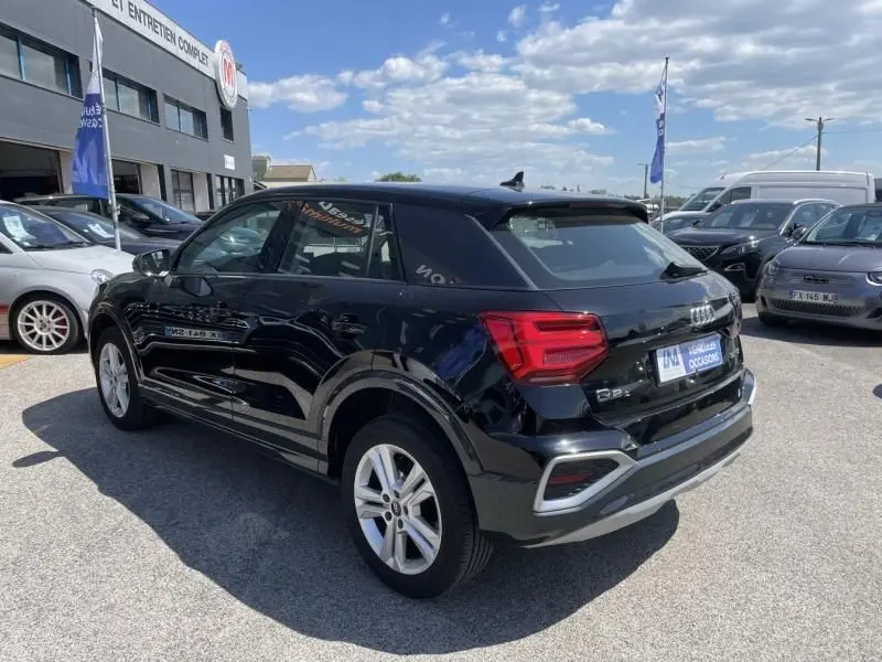 Audi Q2 TFSI 150CV noir métal vue 3/4 arrière droit, avec feux arrière rouges et jantes argentées visibles
