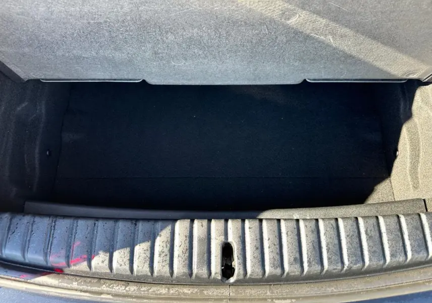 Coffre ouvert vu de dessus d'une BMW Série 1 F40 noire, montrant l'espace de chargement vide et le seuil d'entrée.