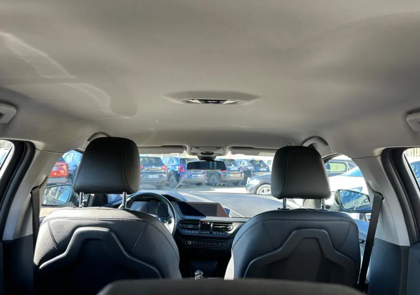 Vue intérieure arrière de la BMW Série 1 noire F40 118d 2021, avec sièges en cuir et tableau de bord moderne.