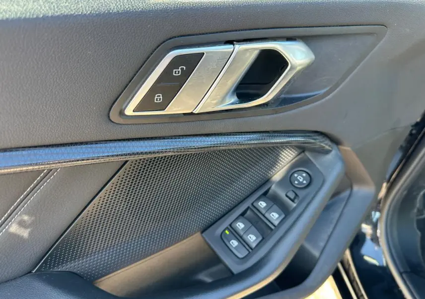 Poignée intérieure côté conducteur de BMW Série 1 noire, avec commandes des vitres et verrouillage centralisé.