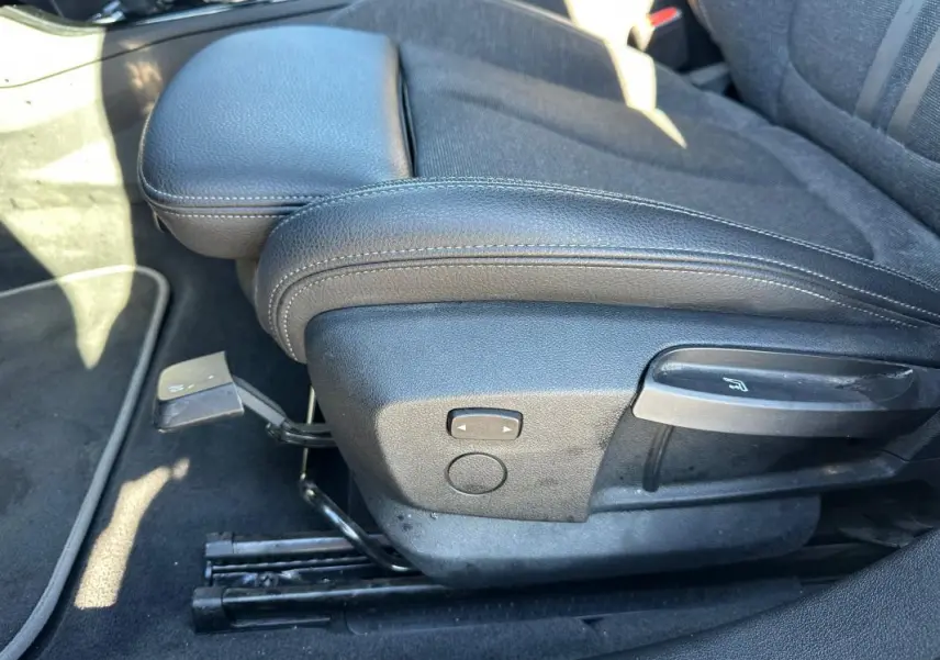 Détail du siège conducteur noir de la BMW Série 1 F40 118d 2021 avec réglage manuel de l'inclinaison et accoudoir central.