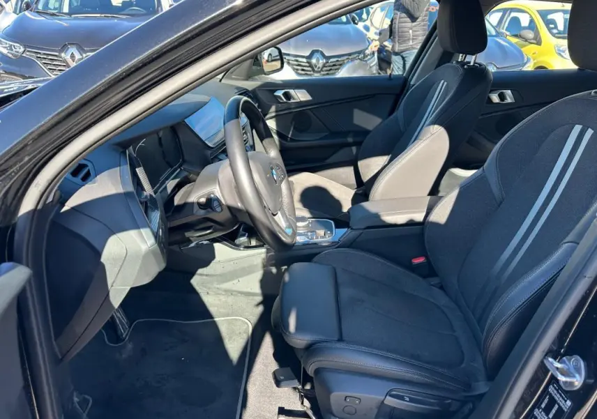 Intérieur BMW Série 1 F40 118d noir, vue côté conducteur montrant sièges sport et tableau de bord moderne.