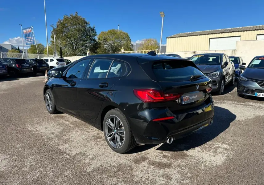 BMW Série 1 F40 118d noire vue en 3/4 arrière droit, avec jantes alliage 17 pouces et double sortie d'échappement chrome.