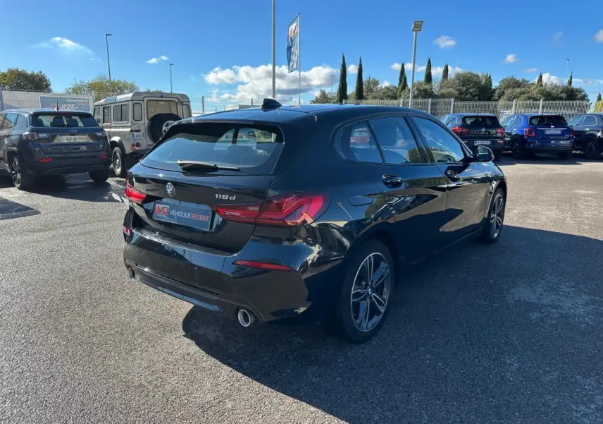 BMW Série 1 F40 118d noire vue en 3/4 arrière droit, avec jantes alliage 17 pouces et double sortie d’échappement.