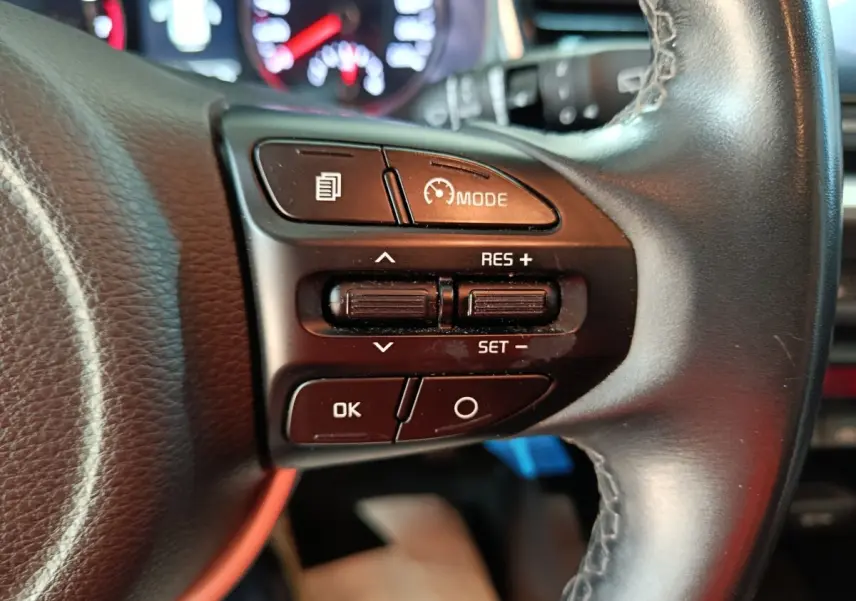 Gros plan sur les commandes de régulateur de vitesse au volant noir du KIA STONIC gris clair, version 2022.