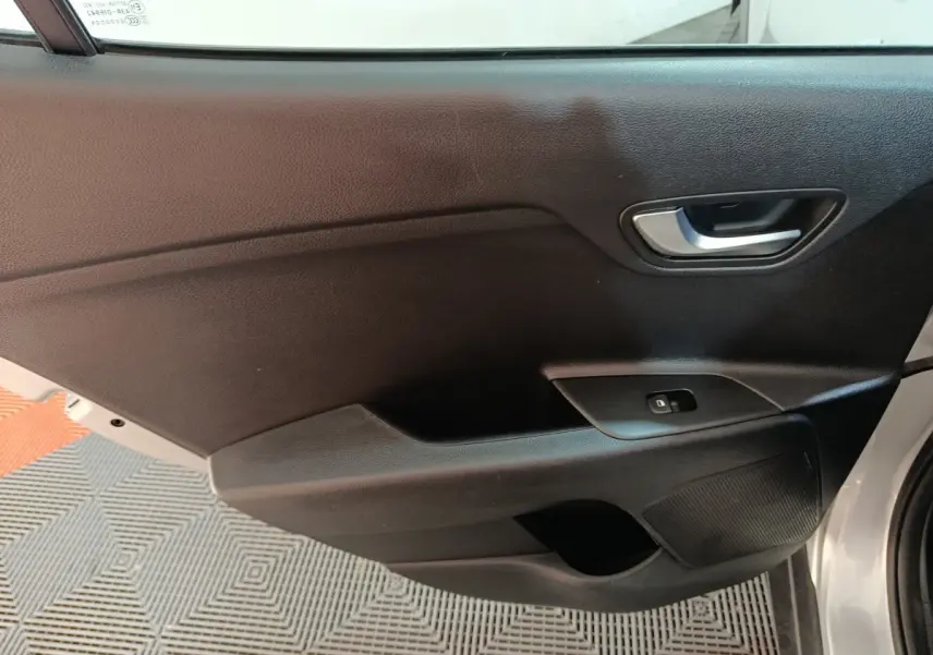 Vue rapprochée de la porte avant droite grise du KIA STONIC 1.0 T-GDI 100 URBAN avec poignée et commande de fenêtre.