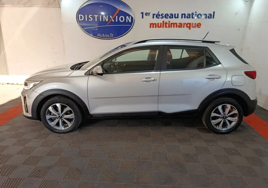Vue de profil côté gauche d'un KIA Stonic gris clair 2022, avec jantes alliage et protections noires sur les passages de roues.