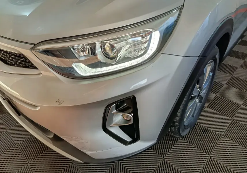Vue rapprochée du coin avant droit d’un KIA Stonic gris clair 2022, mettant en valeur le phare LED et le antibrouillard.