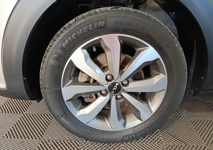 Gros plan sur la roue avant gauche d’un KIA STONIC gris clair, avec jante alliage et pneu Michelin visible.
