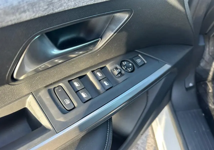 Gros plan sur la commande des vitres et rétroviseurs côté conducteur du Peugeot 3008 Hybrid blanc, intérieur noir.