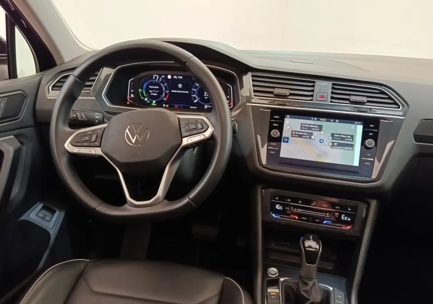 Vue intérieure du tableau de bord et volant noir du Volkswagen Tiguan 1.4 eHybrid 2022 avec écran tactile et affichage numérique.