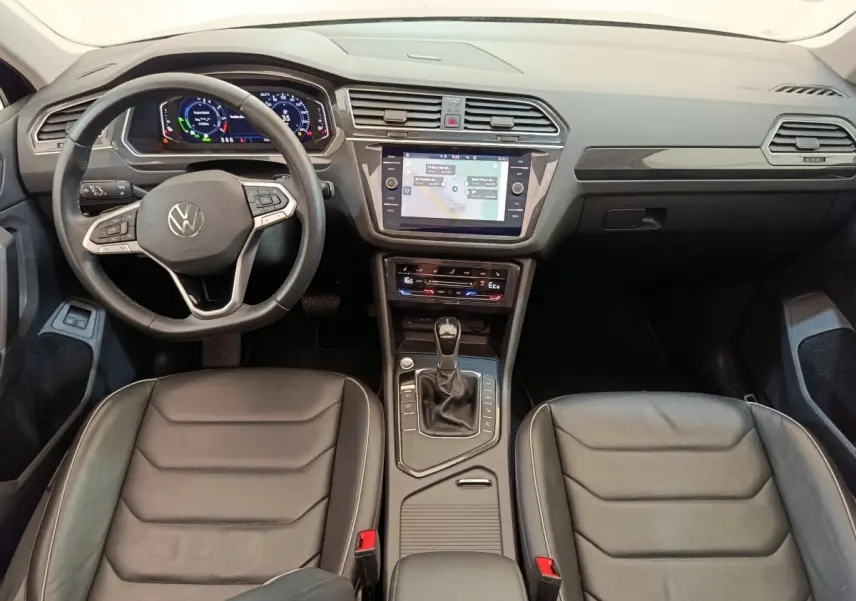 Vue intérieure avant du Volkswagen Tiguan 1.4 eHybrid 2022 avec tableau de bord numérique et sièges en cuir noir.
