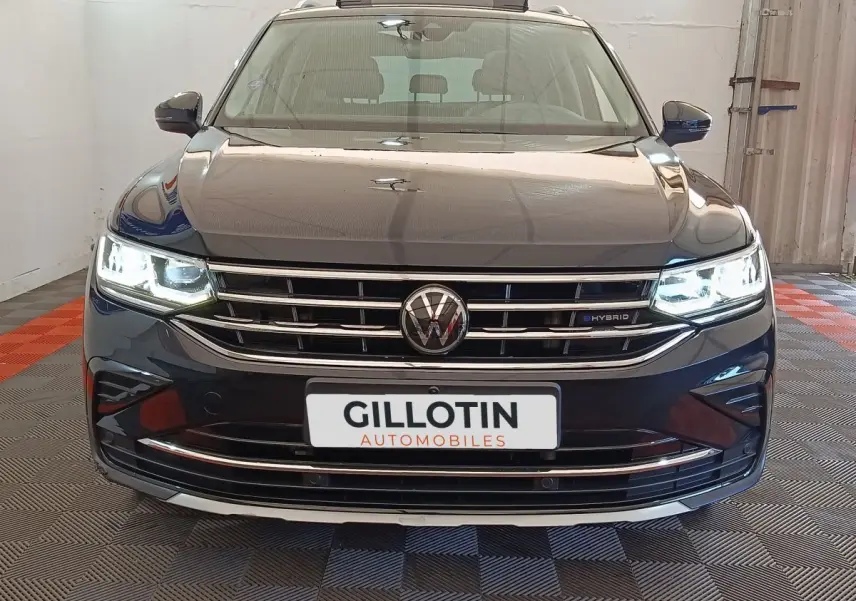 Vue frontale du Volkswagen Tiguan noir hybride rechargeable avec phares LED allumés et calandre chromée.