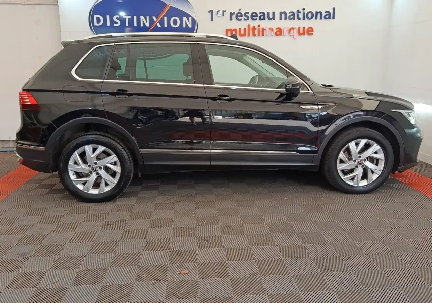 Profil côté gauche d’un Volkswagen Tiguan 1.4 eHybrid noir, avec badge hybride visible sur l’aile avant.