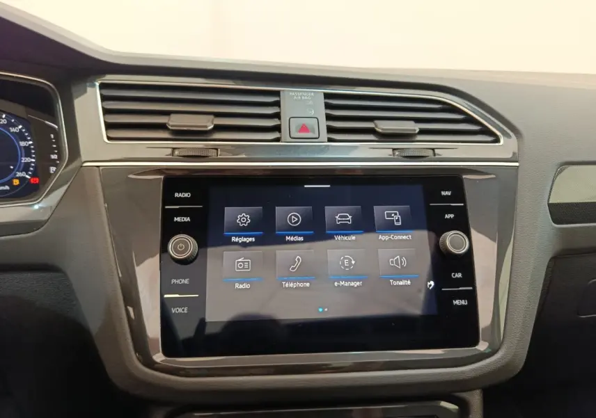 Vue rapprochée du tableau de bord noir du Volkswagen Tiguan 1.4 eHybrid 2022 avec écran tactile central allumé.