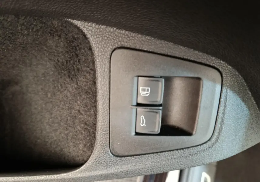 Gros plan sur les boutons d'ouverture du coffre et de la trappe à carburant dans un Volkswagen Tiguan noir 2022.