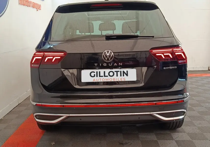 Vue arrière d'un Volkswagen Tiguan noir hybride rechargeable avec feux LED distinctifs et logo central visible.