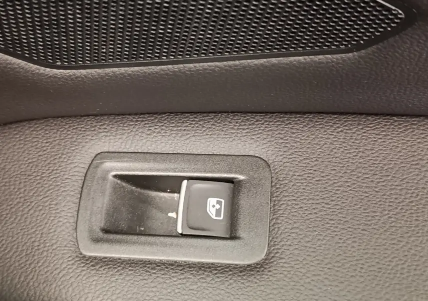 Gros plan sur le bouton de commande de vitre électrique sur la porte intérieure noire d’un Volkswagen Tiguan 2022.