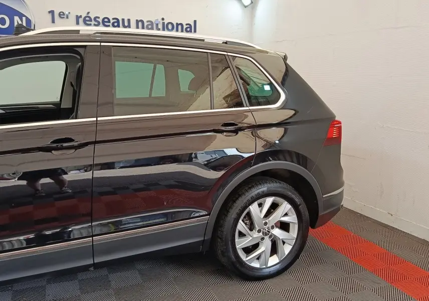 Vue latérale droite du Volkswagen Tiguan noir 2022, mettant en valeur la roue arrière et les vitres teintées.