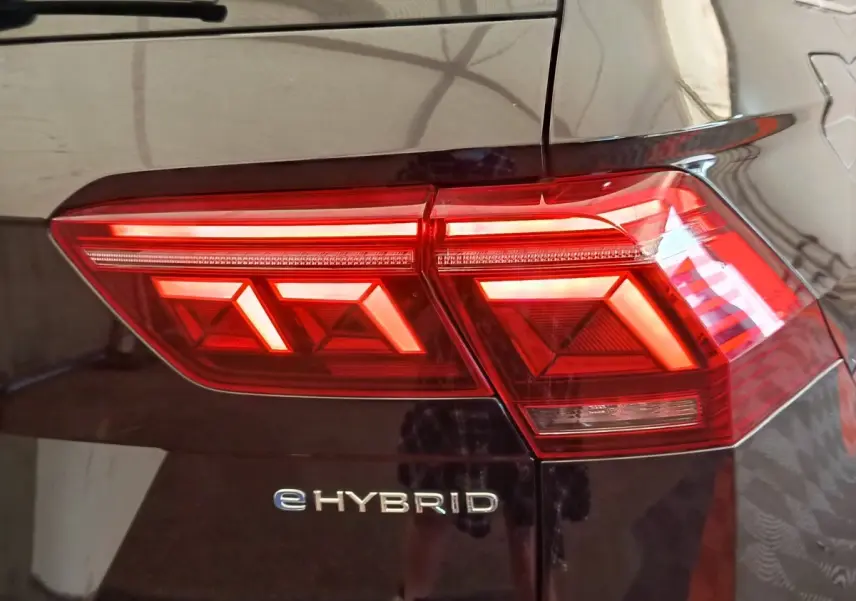Gros plan sur le feu arrière droit rouge et le logo eHybrid d’un Volkswagen Tiguan noir 2022.